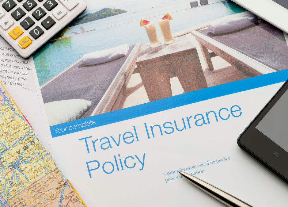 A document titled "Travel Insurance Policy" featuring a picture of a tropical resort sits surrounded by a calculator, a road map, a silver pen, and a smartphone - www.hoffmaninsurance.com